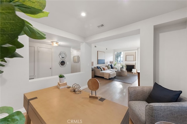 interior space with baseboards, visible vents, wood finished floors, a fireplace, and recessed lighting