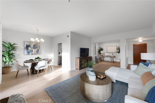 living area with baseboards, light wood finished floors, and an inviting chandelier