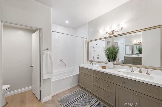 full bathroom with toilet, wood finished floors, a sink, double vanity, and shower / bath combo