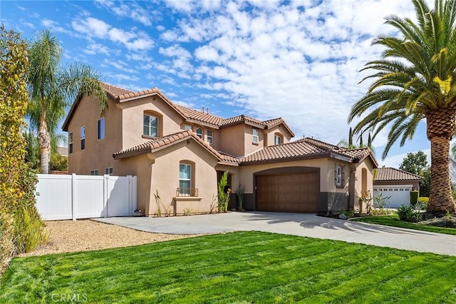 mediterranean / spanish-style house with an attached garage, fence, driveway, stucco siding, and a front lawn