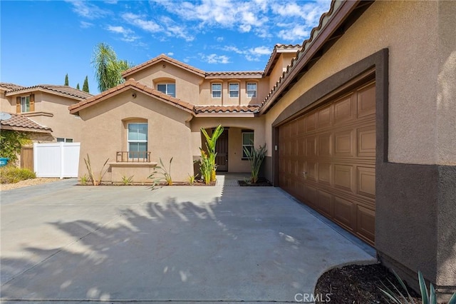 view of front of property with stucco siding, fence, a garage, driveway, and a tiled roof