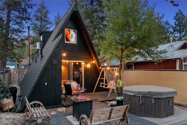 rear view of house featuring a hot tub, a deck, and fence