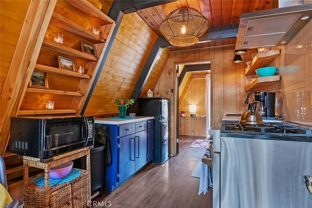 kitchen featuring open shelves, stainless steel gas stove, wood walls, and freestanding refrigerator