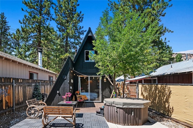 back of house featuring outdoor dining space, a patio, a fenced backyard, and a hot tub