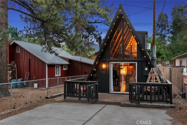 back of property featuring a wooden deck, board and batten siding, metal roof, and fence