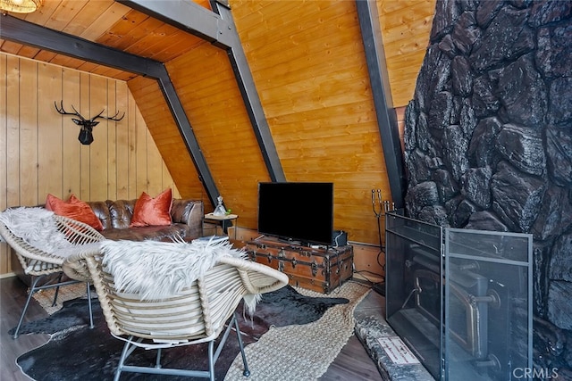 living room with a wood stove, wood finished floors, wooden ceiling, wood walls, and vaulted ceiling with beams