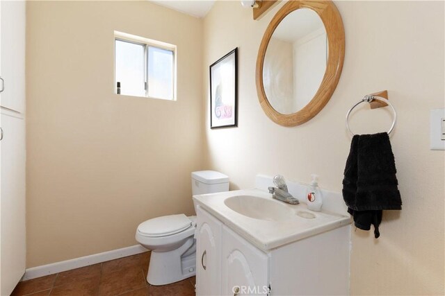 half bath with vanity, tile patterned floors, toilet, and baseboards