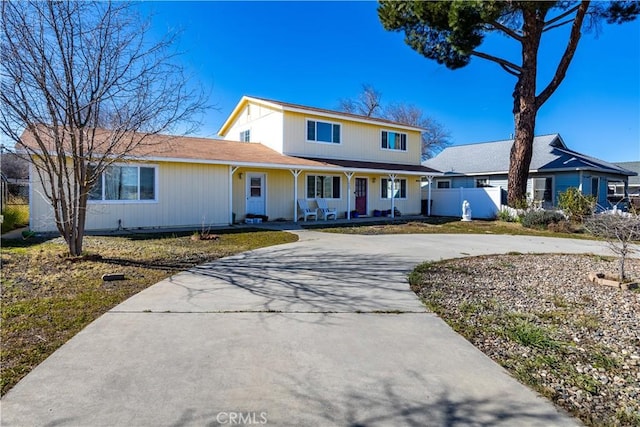 traditional home featuring curved driveway, a porch, and fence