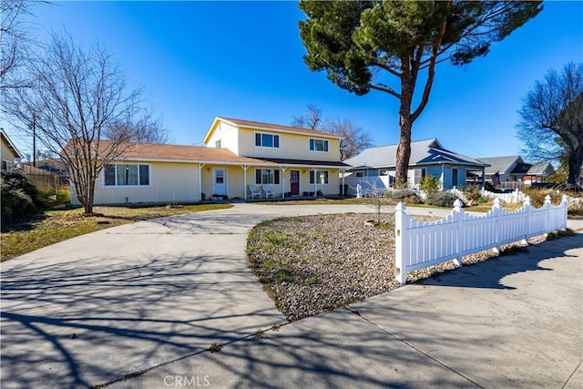 traditional-style house with a fenced front yard and curved driveway
