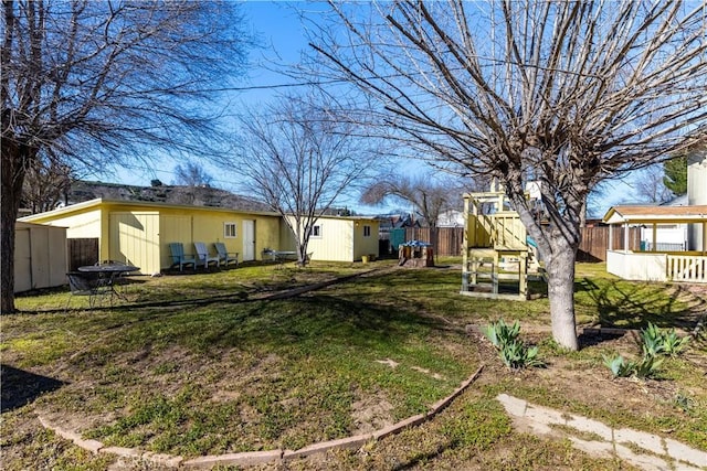 view of yard with a playground, an outdoor structure, and fence