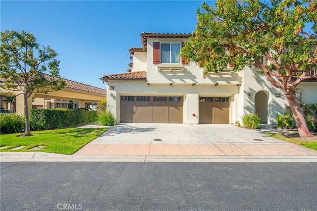 mediterranean / spanish house with a tile roof, stucco siding, concrete driveway, a front yard, and a garage