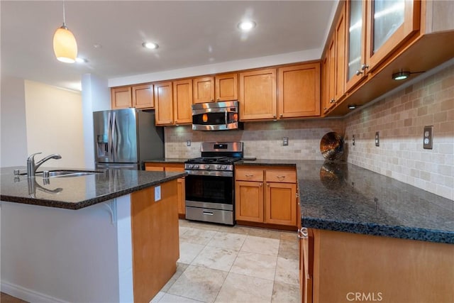 kitchen featuring a sink, stainless steel appliances, brown cabinets, and dark stone countertops