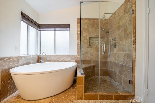 full bath with lofted ceiling, a soaking tub, tile walls, and a stall shower