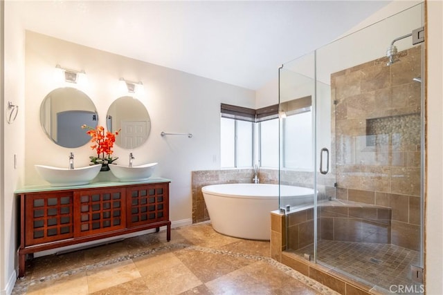 bathroom featuring double vanity, a stall shower, a freestanding bath, and a sink