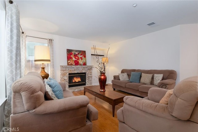 living room with a fireplace, wood finished floors, and visible vents