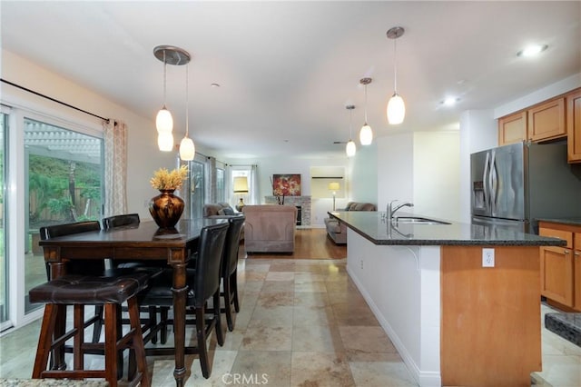 kitchen featuring a kitchen island with sink, a healthy amount of sunlight, stainless steel refrigerator with ice dispenser, and a sink