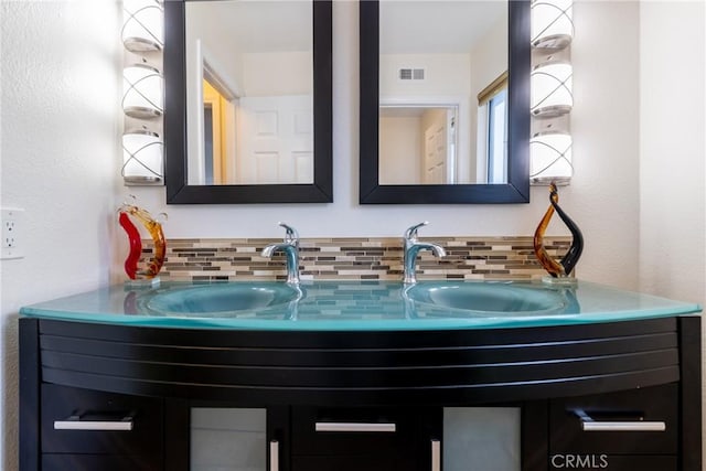 bathroom with double vanity, decorative backsplash, and visible vents