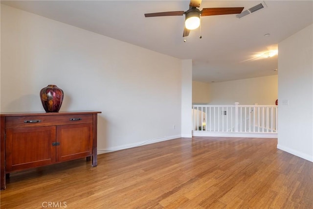 empty room with light wood finished floors, visible vents, baseboards, and a ceiling fan