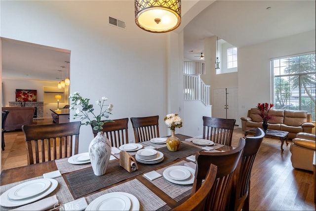 dining room featuring visible vents, a towering ceiling, and wood finished floors