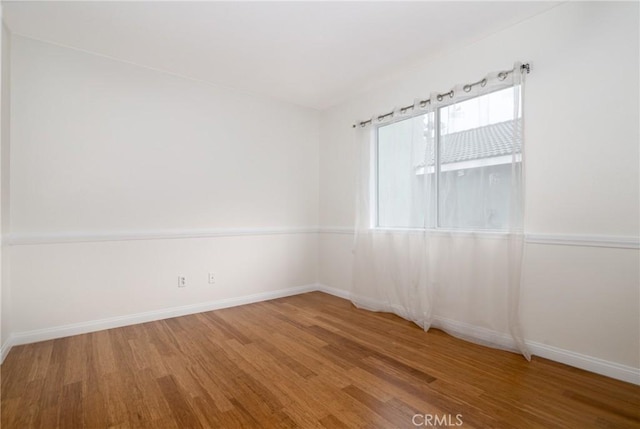 empty room with baseboards and wood finished floors