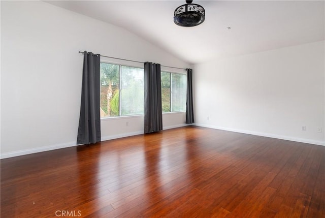 unfurnished room featuring dark wood finished floors, vaulted ceiling, and baseboards