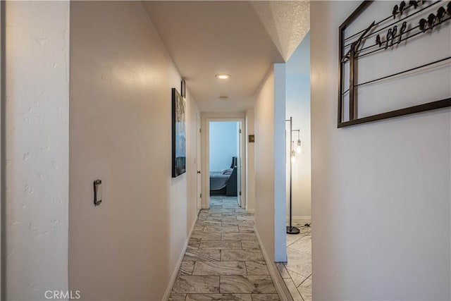 corridor with marble finish floor and baseboards