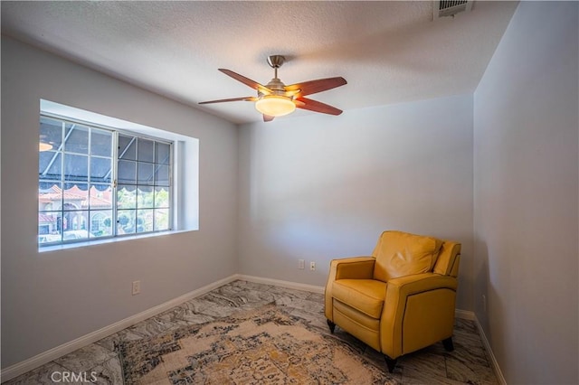 sitting room with a ceiling fan, visible vents, a textured ceiling, and baseboards