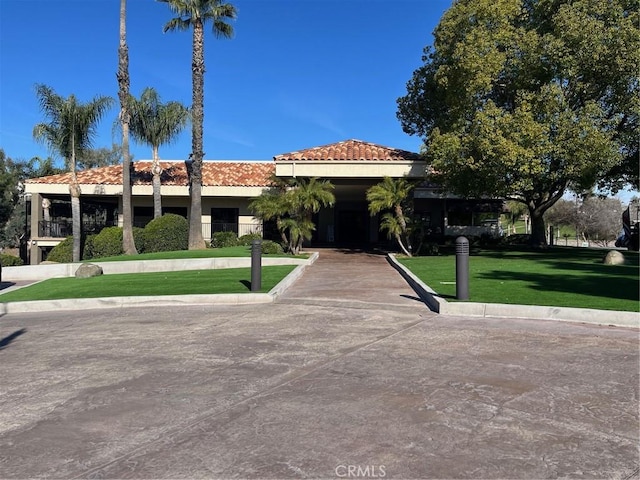 mediterranean / spanish-style home with a tiled roof and a front lawn