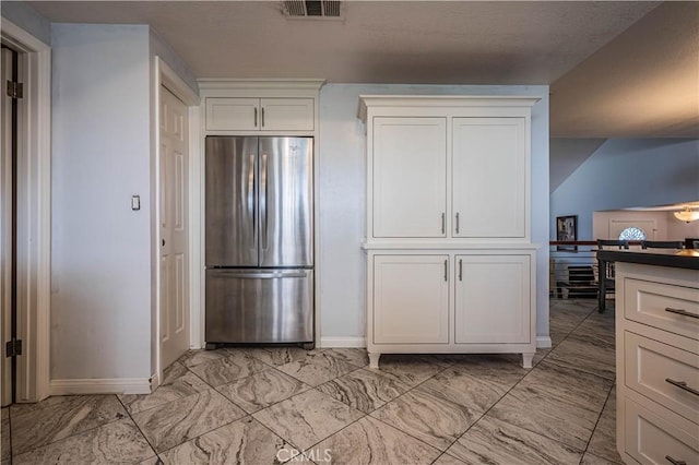 kitchen featuring baseboards, white cabinets, visible vents, stainless steel refrigerator, and marble finish floor