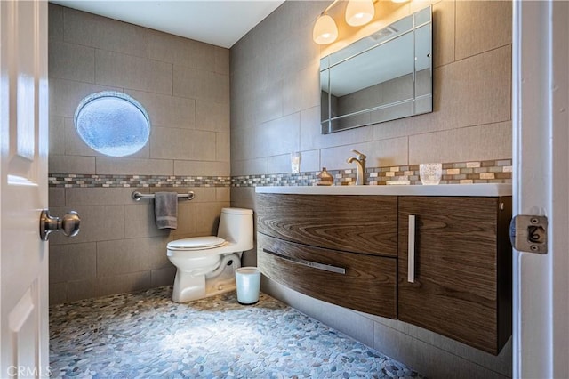 bathroom featuring tile walls, toilet, and vanity