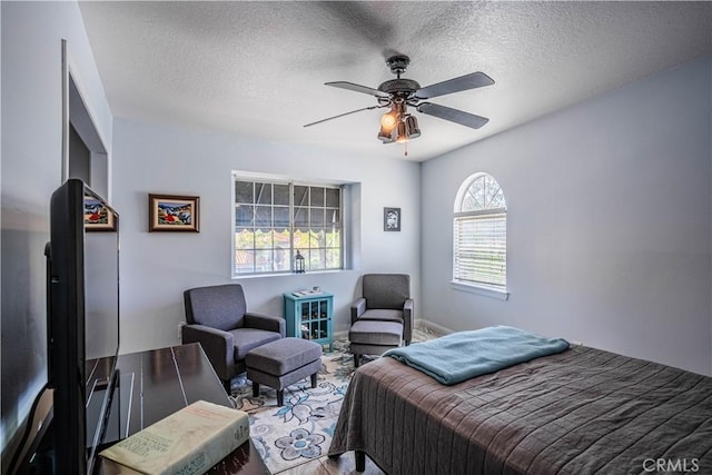 bedroom featuring ceiling fan, baseboards, and a textured ceiling