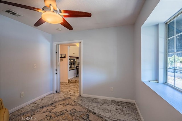 empty room featuring ceiling fan, marble finish floor, visible vents, and baseboards