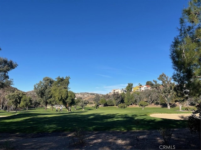 view of home's community with a mountain view, golf course view, and a lawn