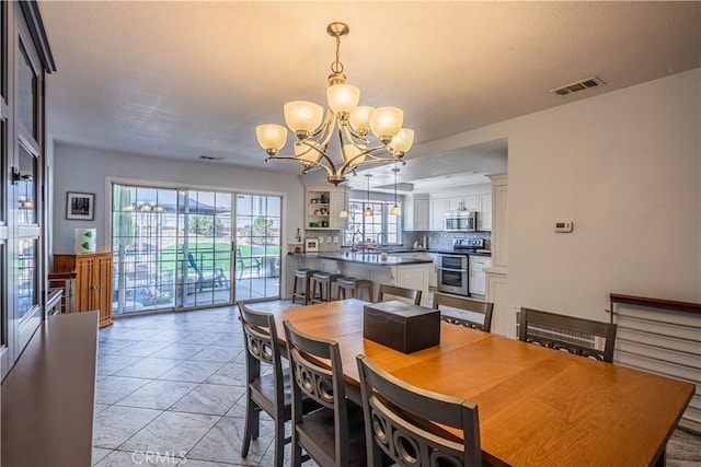 dining room featuring a chandelier, light tile patterned floors, and visible vents