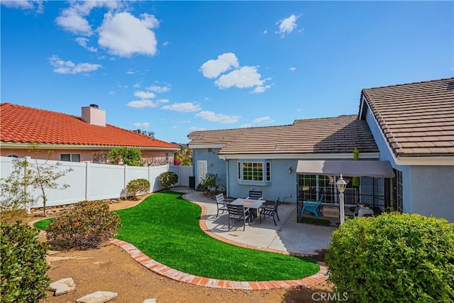 rear view of house with a tile roof, a patio area, a fenced backyard, and stucco siding