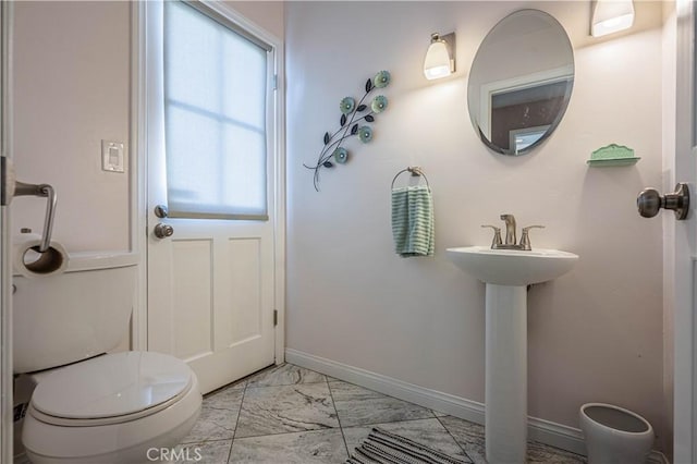 half bath featuring toilet, marble finish floor, and baseboards