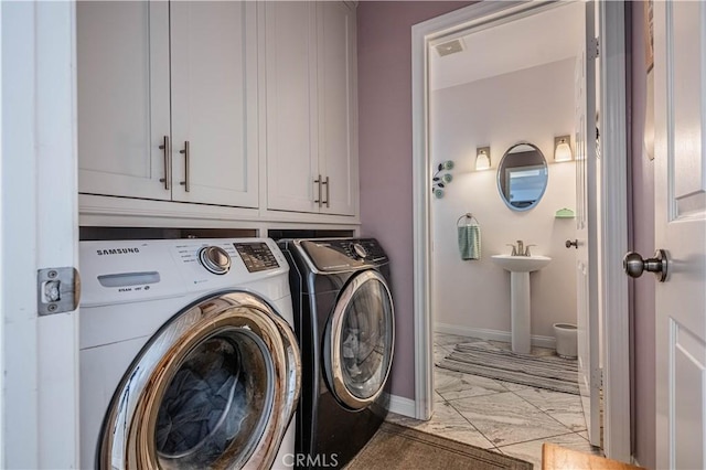 washroom featuring marble finish floor, baseboards, separate washer and dryer, and cabinet space