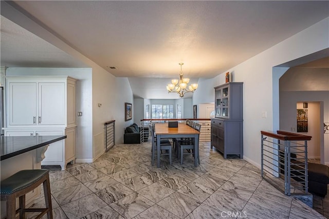 dining space with a chandelier, marble finish floor, and baseboards