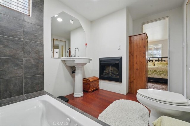 30919 Valley Oak Dr, Running Springs, CA 92382 - ensuite bathroom with wood finished floors, a bathtub, and a glass covered fireplace