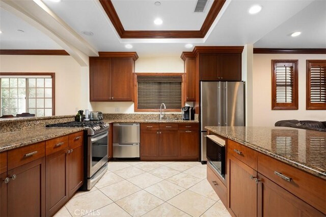 kitchen featuring visible vents, appliances with stainless steel finishes, ornamental molding, a sink, and dark stone countertops