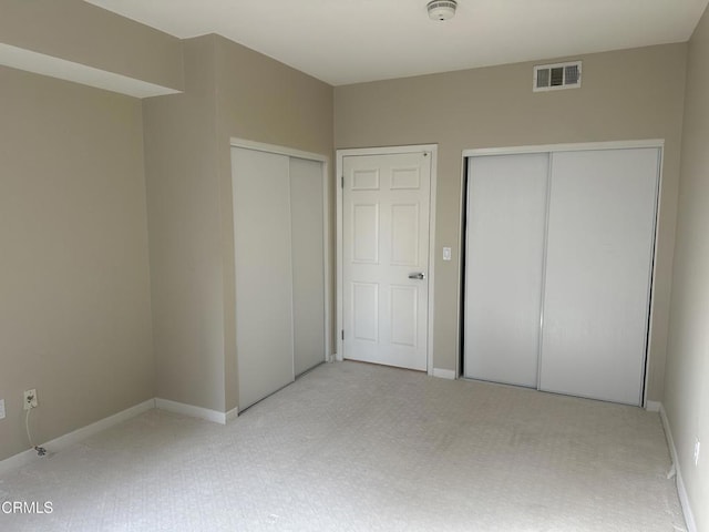 unfurnished bedroom featuring baseboards, visible vents, and multiple closets