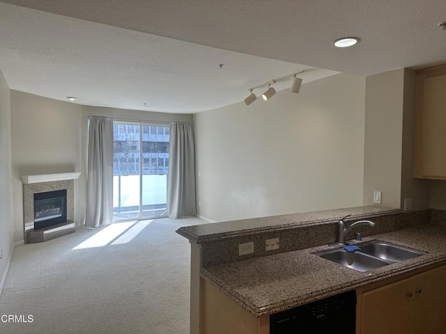 kitchen with light colored carpet, open floor plan, a sink, dishwasher, and a peninsula