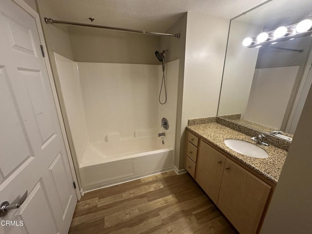 bathroom with a textured ceiling, bathtub / shower combination, wood finished floors, and vanity