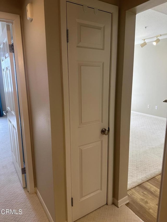 hallway featuring light carpet and baseboards