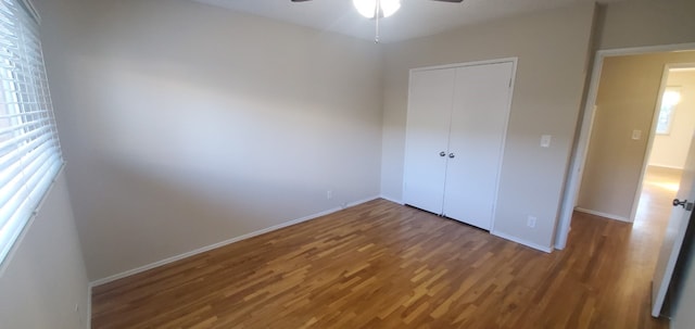 unfurnished bedroom featuring a closet, ceiling fan, baseboards, and wood finished floors