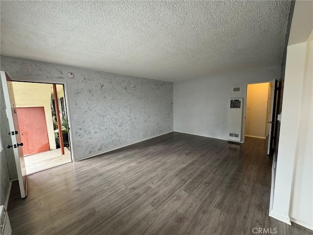 empty room with a textured ceiling, visible vents, and dark wood-type flooring