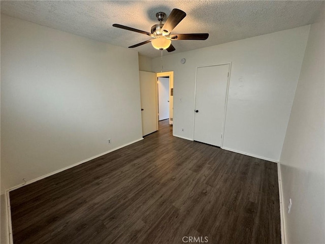 unfurnished bedroom with a textured ceiling, dark wood-type flooring, a ceiling fan, and baseboards