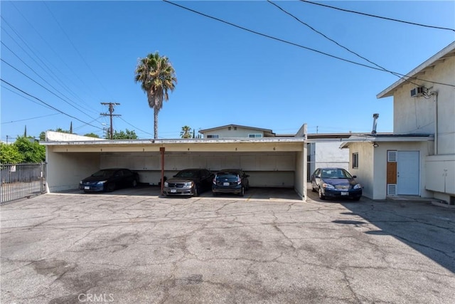 partially covered parking lot featuring fence