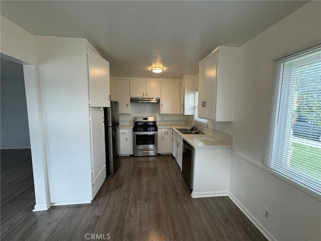 kitchen featuring under cabinet range hood, a sink, light countertops, freestanding refrigerator, and stainless steel gas stove