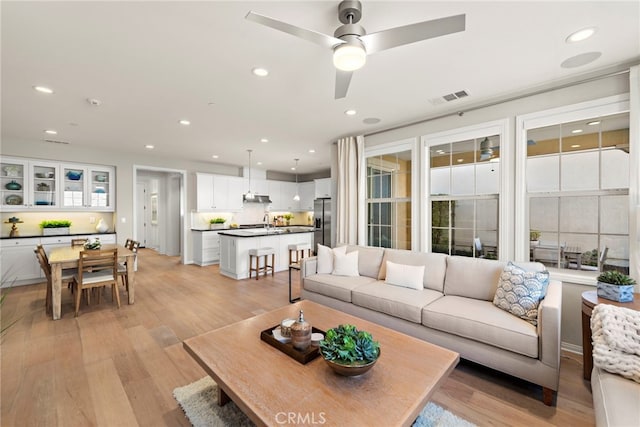 living area with light wood-type flooring, visible vents, a ceiling fan, and recessed lighting